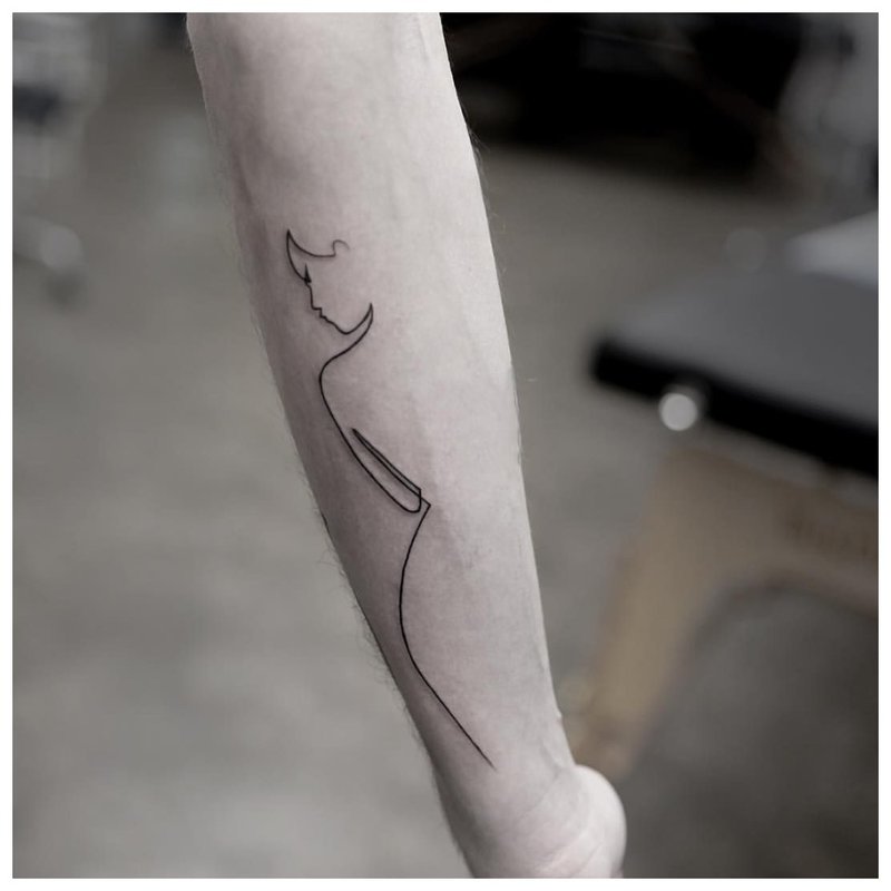 Kvinnesilhuett - tatovering på mannens arm