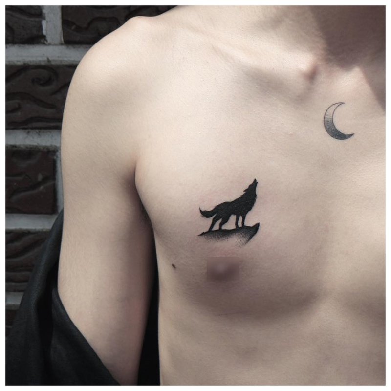 Un lup urlă la lună - un tatuaj pe pieptul unui bărbat